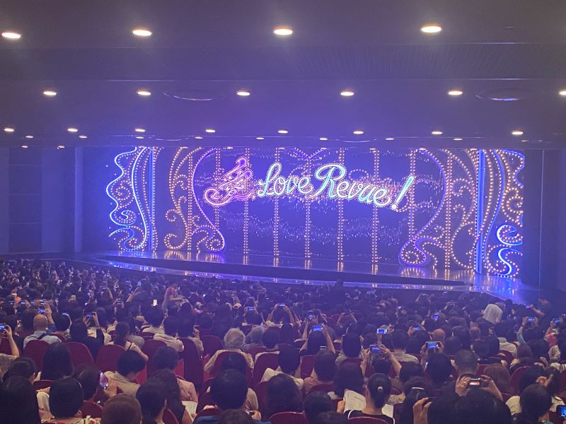 The curtain hasn't been raised yet, so the lights spelling out the I Love Revue logo are still bright and colorful.